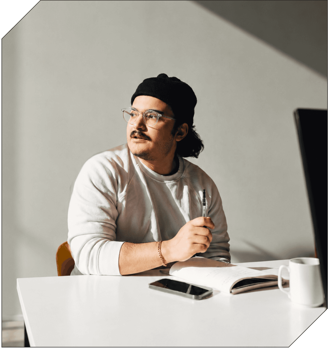 A person with a pen and notebook at a sunlit desk.
